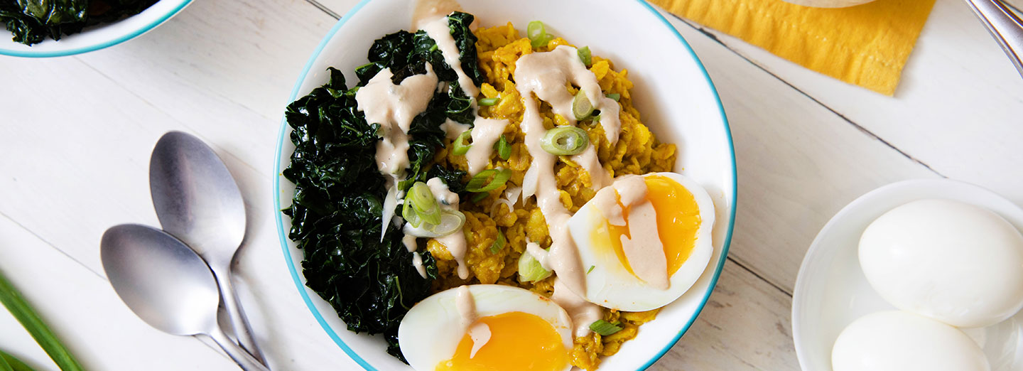 oatmeal, kale, and medium boiled egg in a bowl on a white table top