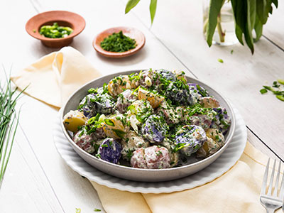 herbed potato salad in bowl on wooden table