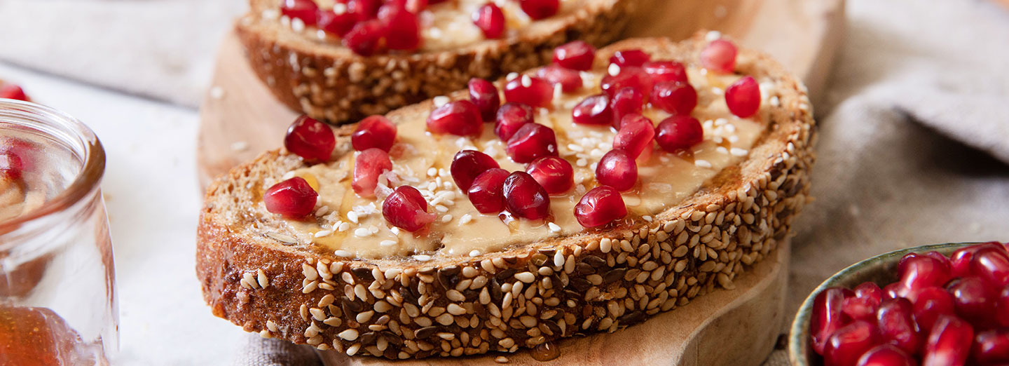 toast with peanut butter, pomegranate seeds and rosemary honey on top
